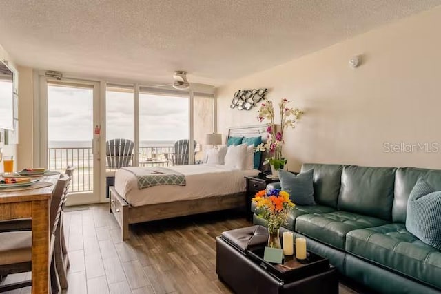 bedroom with access to outside, hardwood / wood-style floors, and a textured ceiling