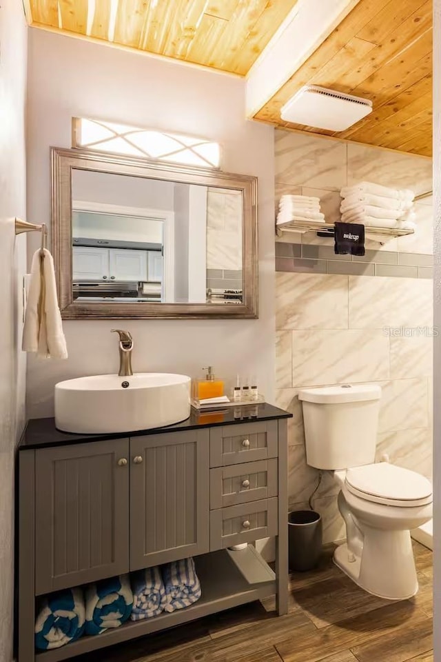 bathroom featuring tile walls, vanity, wood-type flooring, wooden ceiling, and toilet