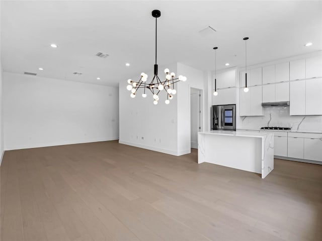 kitchen featuring stainless steel refrigerator with ice dispenser, a center island, hanging light fixtures, white cabinets, and backsplash