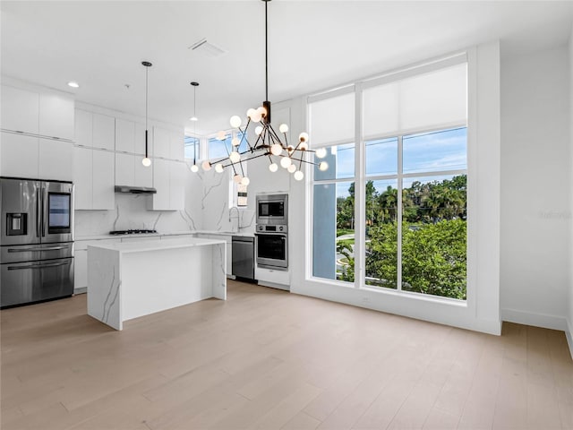 kitchen featuring white cabinetry, an inviting chandelier, decorative light fixtures, appliances with stainless steel finishes, and a kitchen island