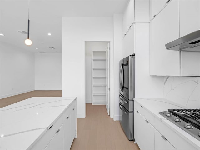 kitchen featuring appliances with stainless steel finishes, white cabinetry, light stone counters, tasteful backsplash, and decorative light fixtures