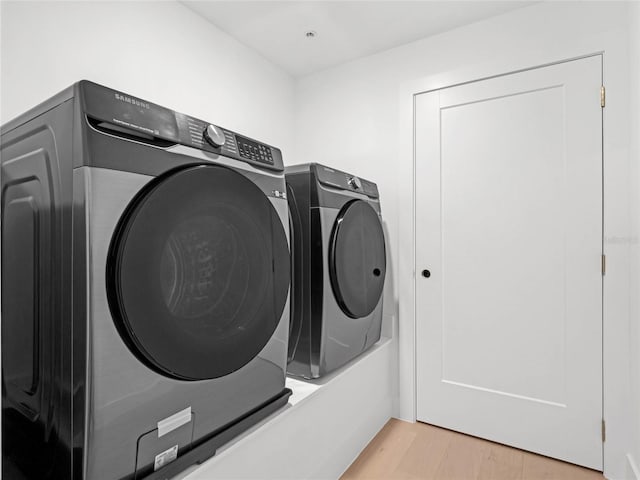 laundry room featuring light hardwood / wood-style floors and washing machine and clothes dryer