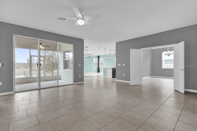 tiled spare room featuring ceiling fan with notable chandelier