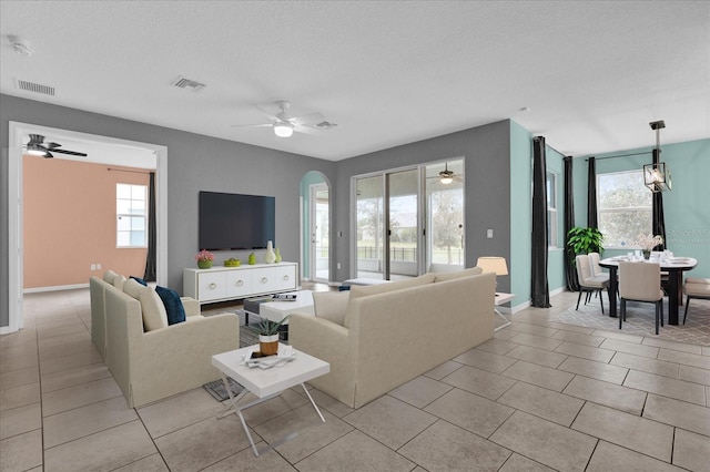 tiled living room with ceiling fan, a wealth of natural light, and a textured ceiling