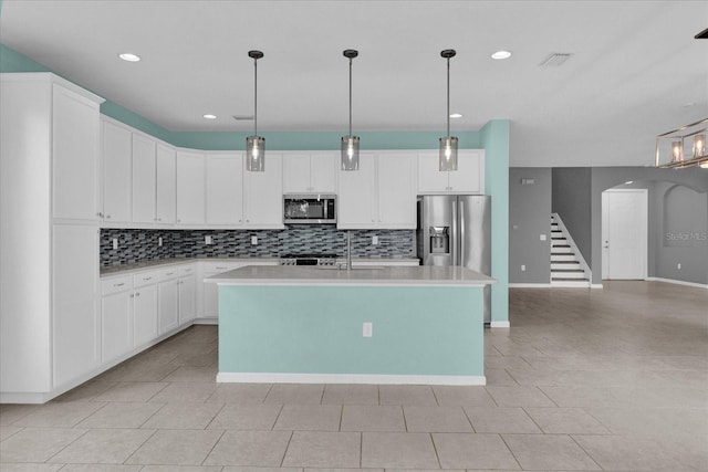 kitchen with white cabinetry, stainless steel appliances, a center island with sink, and pendant lighting