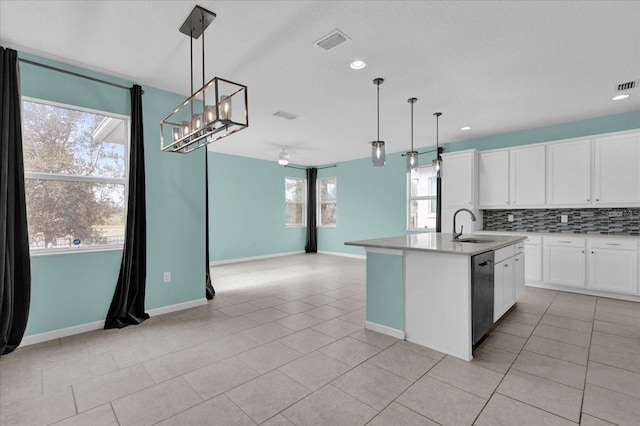 kitchen with white cabinetry, hanging light fixtures, a center island with sink, stainless steel dishwasher, and decorative backsplash