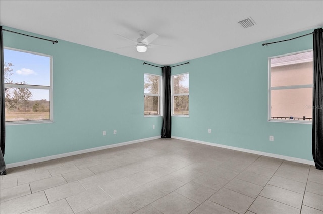 spare room with a healthy amount of sunlight, light tile patterned floors, and ceiling fan