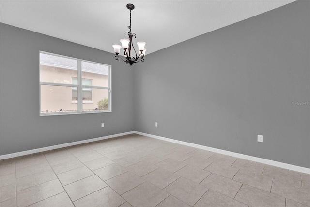 spare room featuring light tile patterned floors and a chandelier