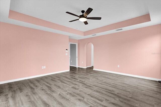 unfurnished room featuring hardwood / wood-style flooring, ceiling fan, and a tray ceiling