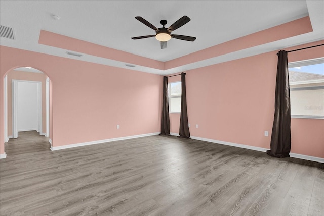 empty room featuring a tray ceiling, light hardwood / wood-style flooring, and ceiling fan