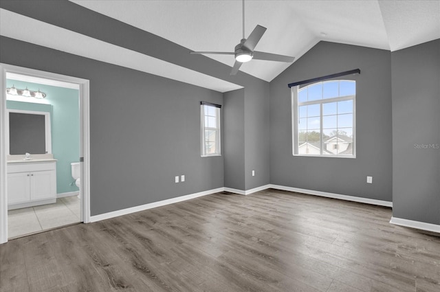 spare room featuring lofted ceiling, a healthy amount of sunlight, and wood-type flooring