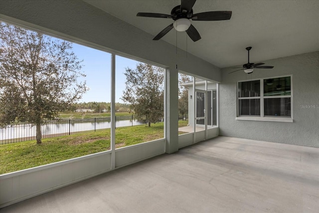 unfurnished sunroom featuring a water view and ceiling fan