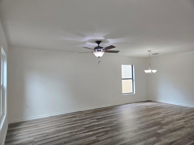 unfurnished room with ceiling fan with notable chandelier and dark hardwood / wood-style floors