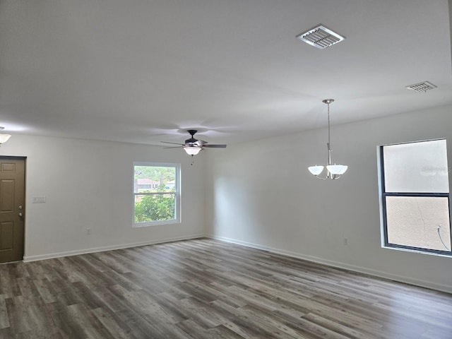 unfurnished room with ceiling fan with notable chandelier and dark hardwood / wood-style flooring