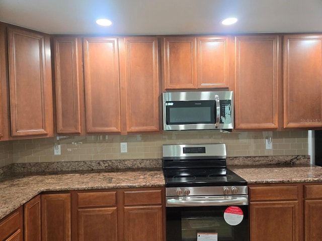 kitchen featuring stainless steel appliances, stone countertops, and decorative backsplash