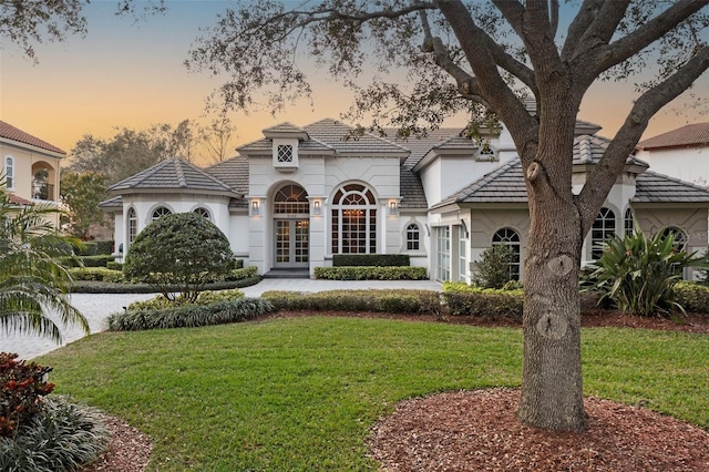 view of front facade with french doors and a lawn