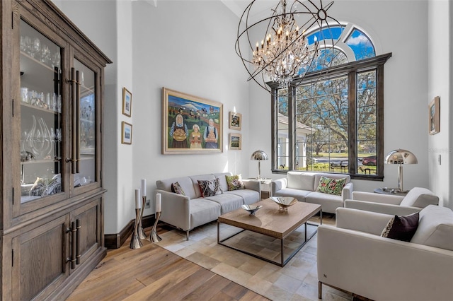 living room featuring a towering ceiling, light hardwood / wood-style flooring, and a chandelier