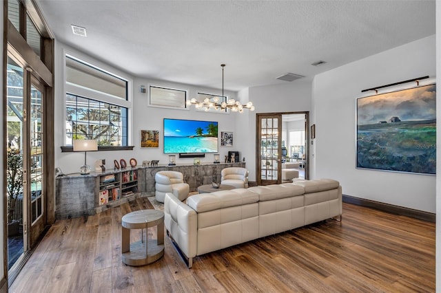 living room featuring hardwood / wood-style floors, a notable chandelier, and a textured ceiling