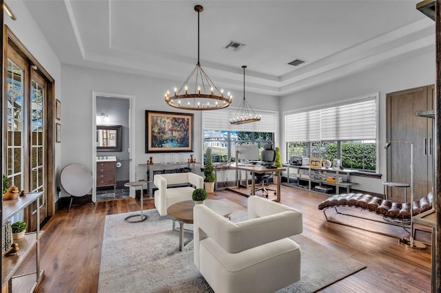 living room featuring an inviting chandelier, a tray ceiling, and hardwood / wood-style flooring