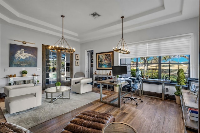 home office featuring an inviting chandelier, a tray ceiling, and hardwood / wood-style flooring