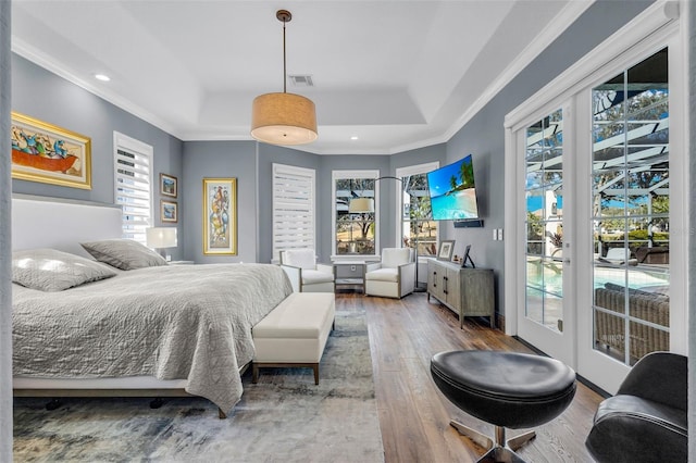 bedroom with a raised ceiling, hardwood / wood-style flooring, access to outside, and french doors