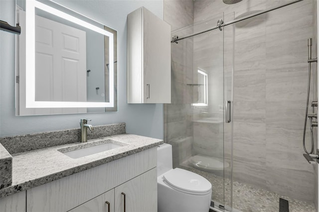 bathroom with vanity, toilet, and a shower with door