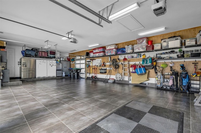 garage with a garage door opener and stainless steel refrigerator with ice dispenser