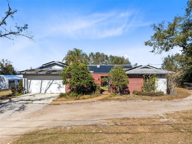 ranch-style house featuring a garage and solar panels