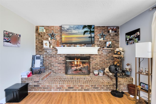 living room featuring a textured ceiling, a fireplace, and wood-type flooring