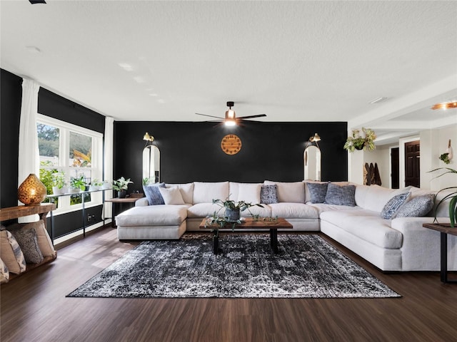 living room with ceiling fan, dark hardwood / wood-style floors, and a textured ceiling