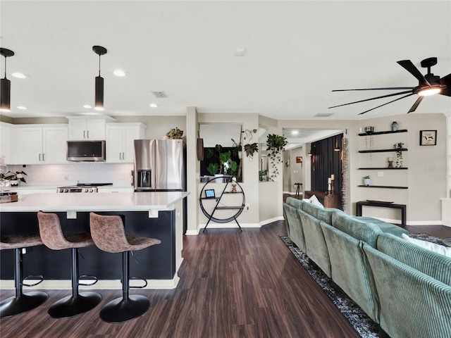 kitchen featuring white cabinetry, dark hardwood / wood-style flooring, pendant lighting, stainless steel appliances, and decorative backsplash