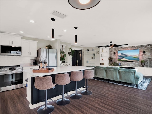 kitchen with a breakfast bar area, a center island, appliances with stainless steel finishes, pendant lighting, and white cabinets