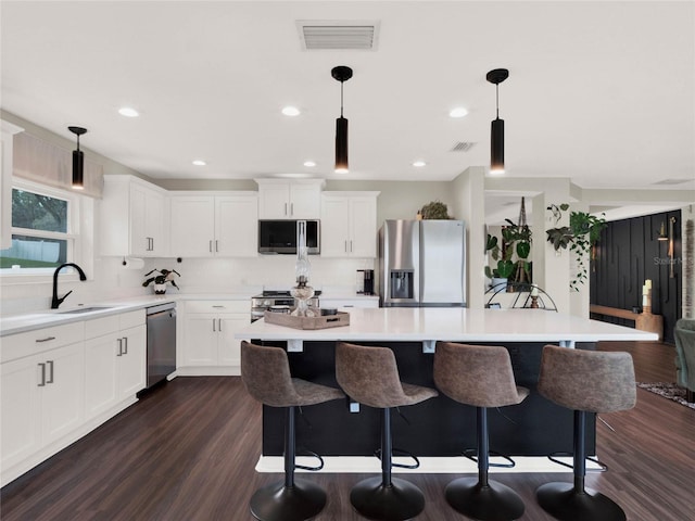 kitchen featuring stainless steel appliances, a center island, pendant lighting, and white cabinets