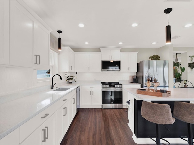 kitchen featuring hanging light fixtures, stainless steel appliances, sink, and white cabinets