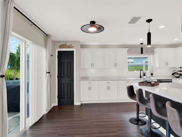 kitchen with pendant lighting, sink, dishwasher, dark hardwood / wood-style floors, and white cabinets