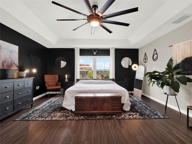 bedroom featuring dark wood-type flooring, ceiling fan, and a raised ceiling