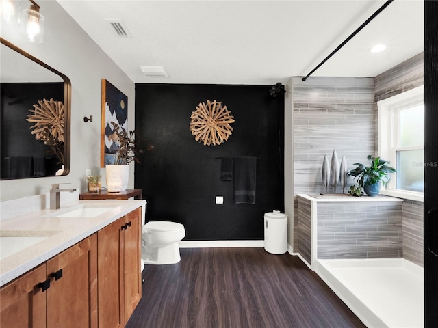 bathroom with hardwood / wood-style flooring, vanity, toilet, and a shower