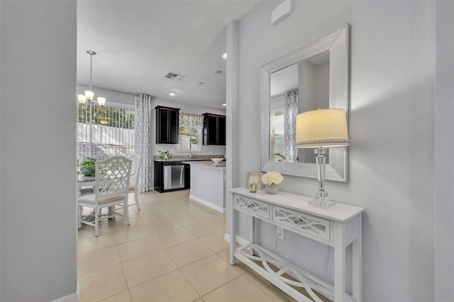 corridor featuring a wealth of natural light, a chandelier, and light tile patterned floors