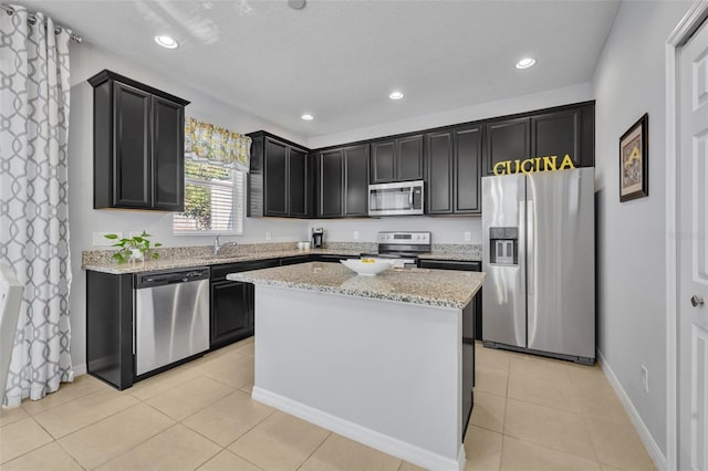 kitchen with light tile patterned flooring, a kitchen island, sink, stainless steel appliances, and light stone countertops