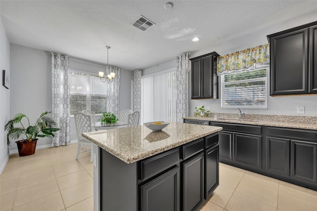 kitchen with a kitchen island, sink, light tile patterned floors, and pendant lighting