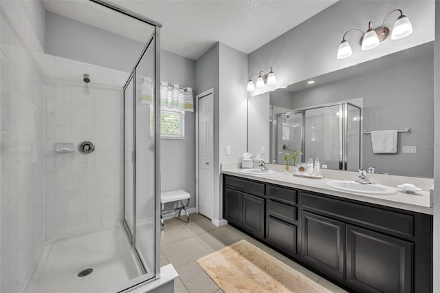 bathroom with tile patterned floors, a shower with shower door, vanity, and a textured ceiling