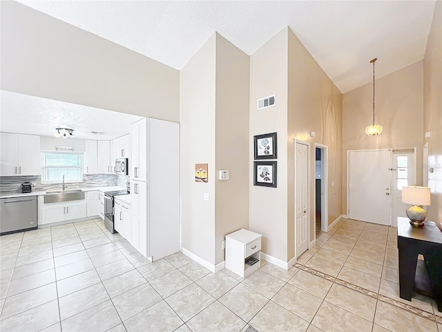 kitchen featuring white cabinetry, sink, light tile patterned floors, and appliances with stainless steel finishes