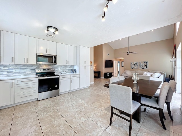 kitchen with white cabinetry, stainless steel appliances, vaulted ceiling, and decorative backsplash