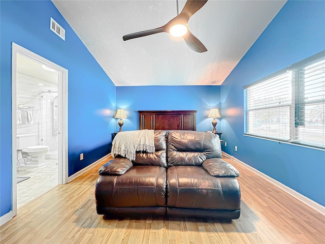 bedroom with vaulted ceiling, ensuite bathroom, ceiling fan, a textured ceiling, and light hardwood / wood-style flooring