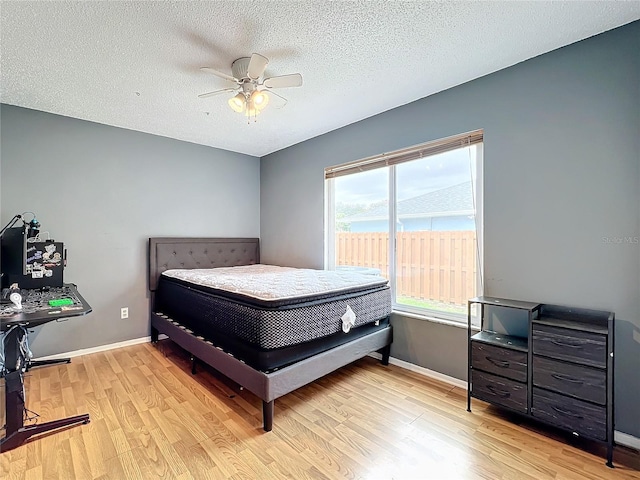 bedroom featuring ceiling fan, a textured ceiling, and light hardwood / wood-style floors