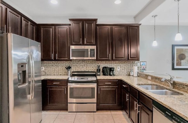 kitchen featuring tasteful backsplash, decorative light fixtures, stainless steel appliances, dark brown cabinets, and a sink