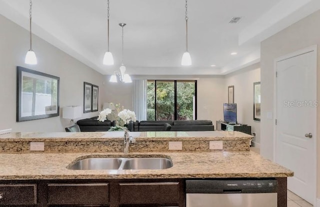 kitchen featuring decorative light fixtures, open floor plan, a sink, light stone countertops, and dishwasher