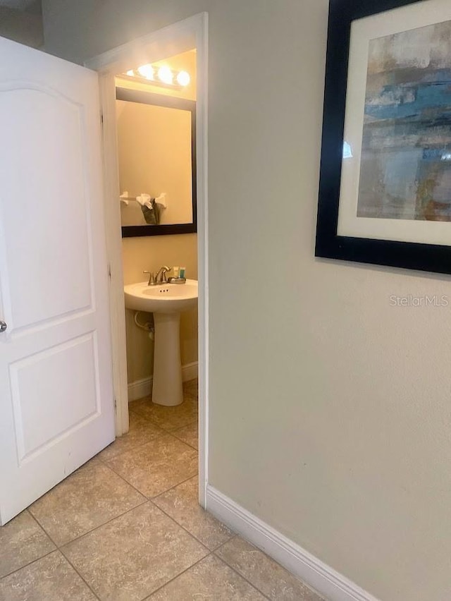 interior space featuring a sink, baseboards, and light tile patterned floors