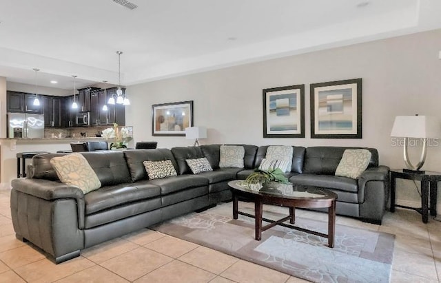 living area featuring light tile patterned floors, a raised ceiling, and visible vents