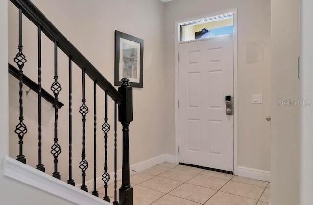 entrance foyer featuring stairs, light tile patterned floors, and baseboards